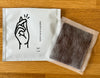 Home recyclable packaging bag with hand illustration and an opened tea bag on wooden surface.