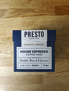Presto Coffee House Espresso bags on wooden surface, featuring barista grade dark roast with chocolate, peanut, and caramel tasting notes.