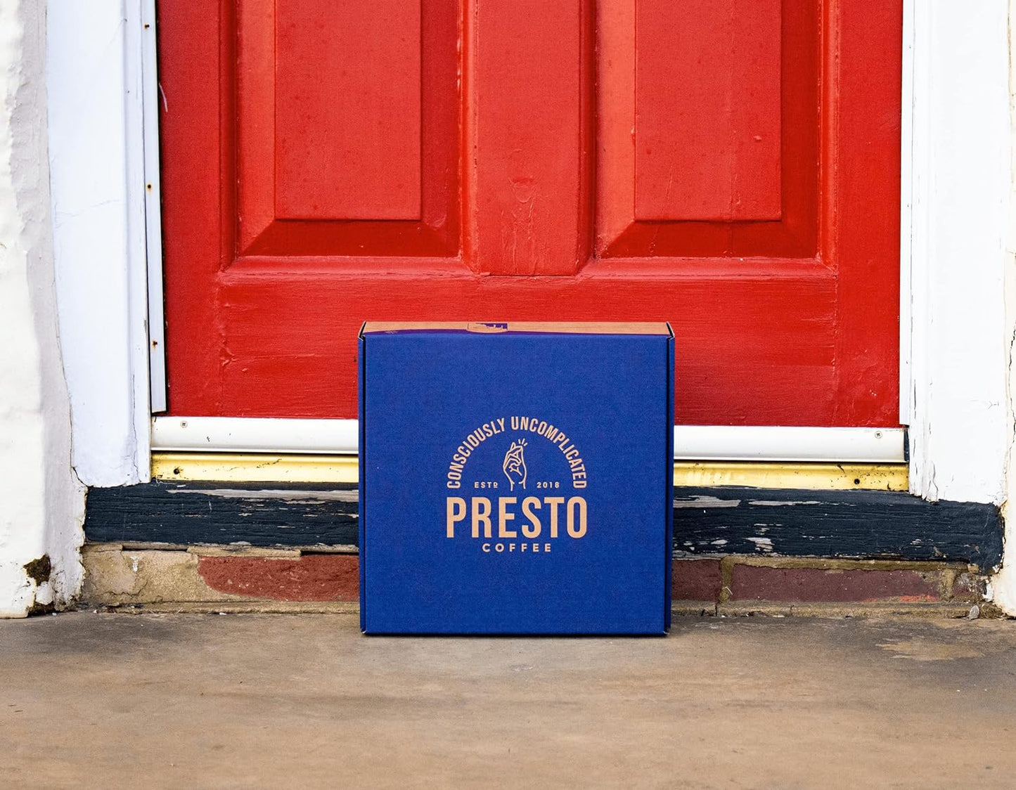 Box of Presto Coffee with logo placed on doorstep in front of a red door.