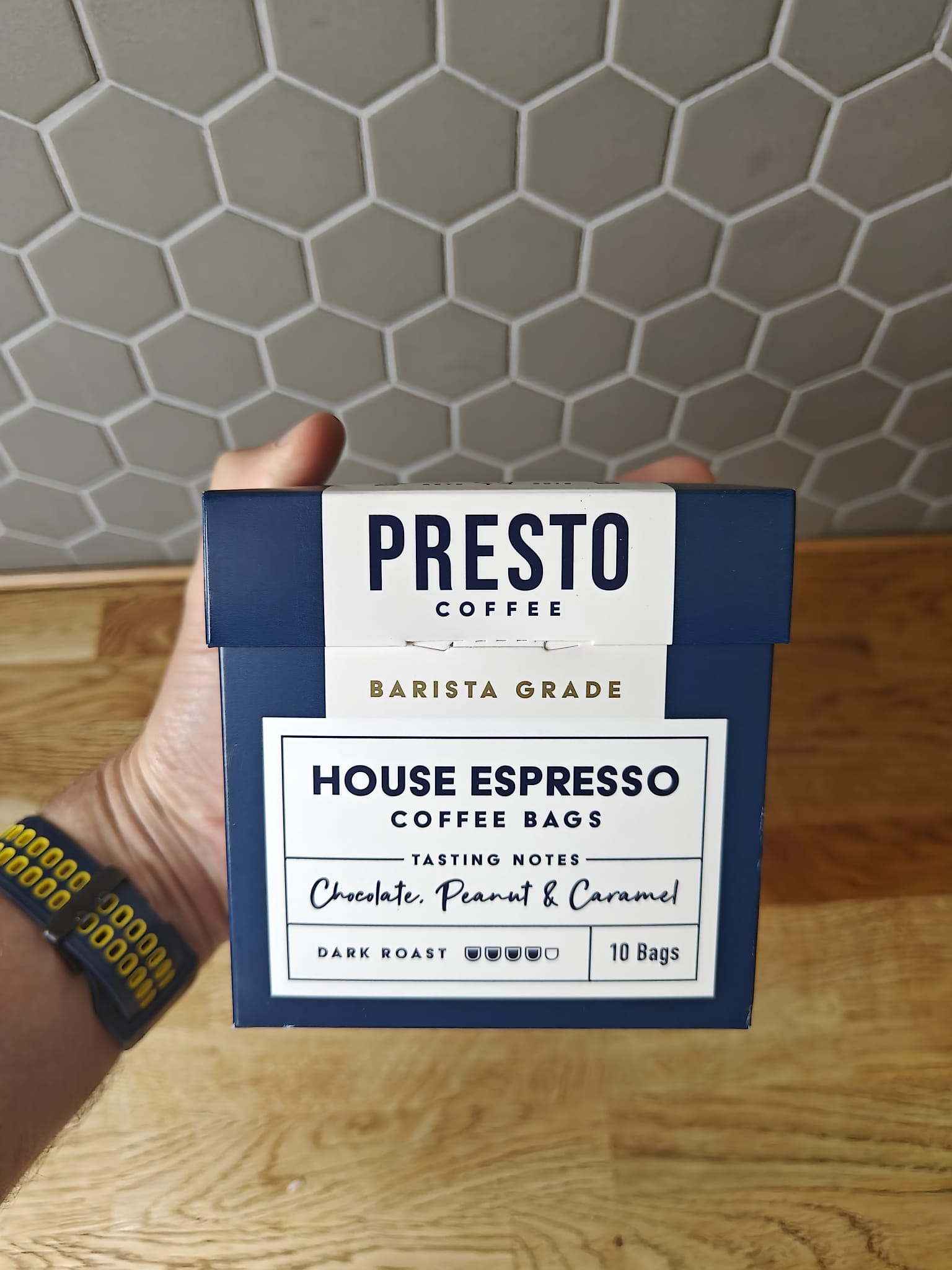 Presto Coffee House Espresso coffee bags packaging with tasting notes of chocolate, peanut, and caramel, barista-grade dark roast, hexagonal tile background.